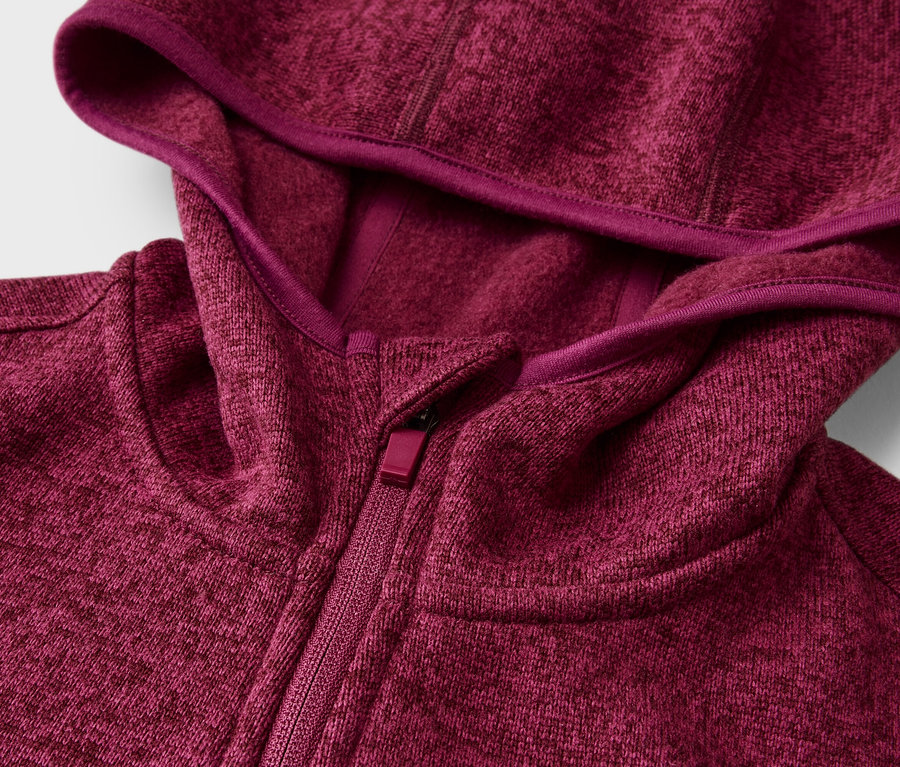 Gros plan d'une veste à capuche chinée magenta avec une fermeture éclair, la capuche est bordée d'un ruban magenta plus foncé.
