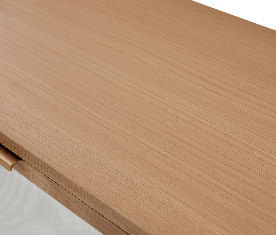 Gros plan d'une surface en bois clair avec grain visible, montrant une surface blanche et un bord en bois arrondi en bas à gauche.