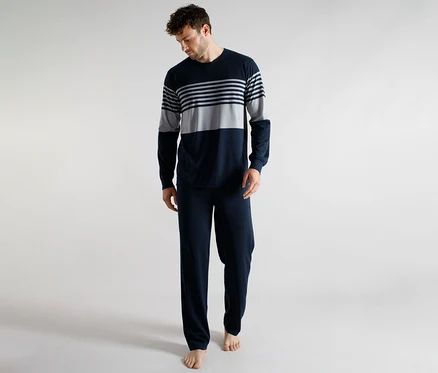 Homme portant un haut de pyjama à manches longues rayé bleu marine et gris et un pantalon de pyjama uni bleu marine, regardant vers le bas.