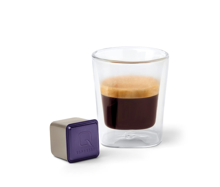 Une capsule Qbo Espresso CAFEZINHO DO BRASIL est à côté d'un verre d'espresso.