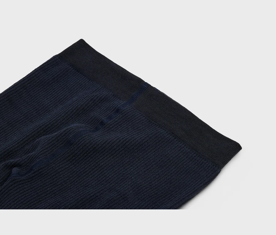 Tissu côtelé bleu foncé avec une bande élastique plus foncée sur le bord supérieur, présentant une texture verticale et de légers plis.