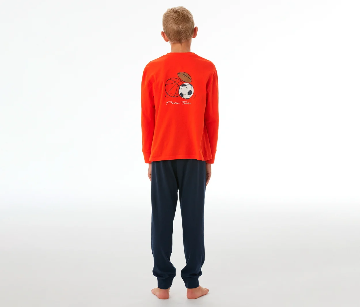 Garçon portant un pyjama enfant SCHIESSER à poignets, haut orange avec motif de ballons de sport et pantalon bleu marine.
