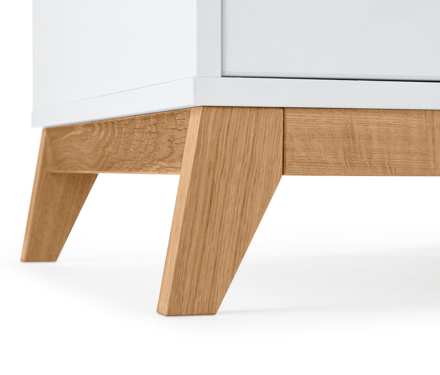 Gros plan sur la partie inférieure d'une armoire blanche avec des pieds en bois.