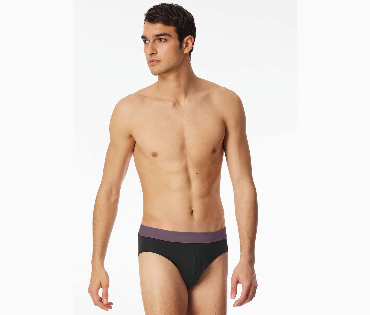Homme torse nu portant un slip noir Schiesser avec une ceinture violette.