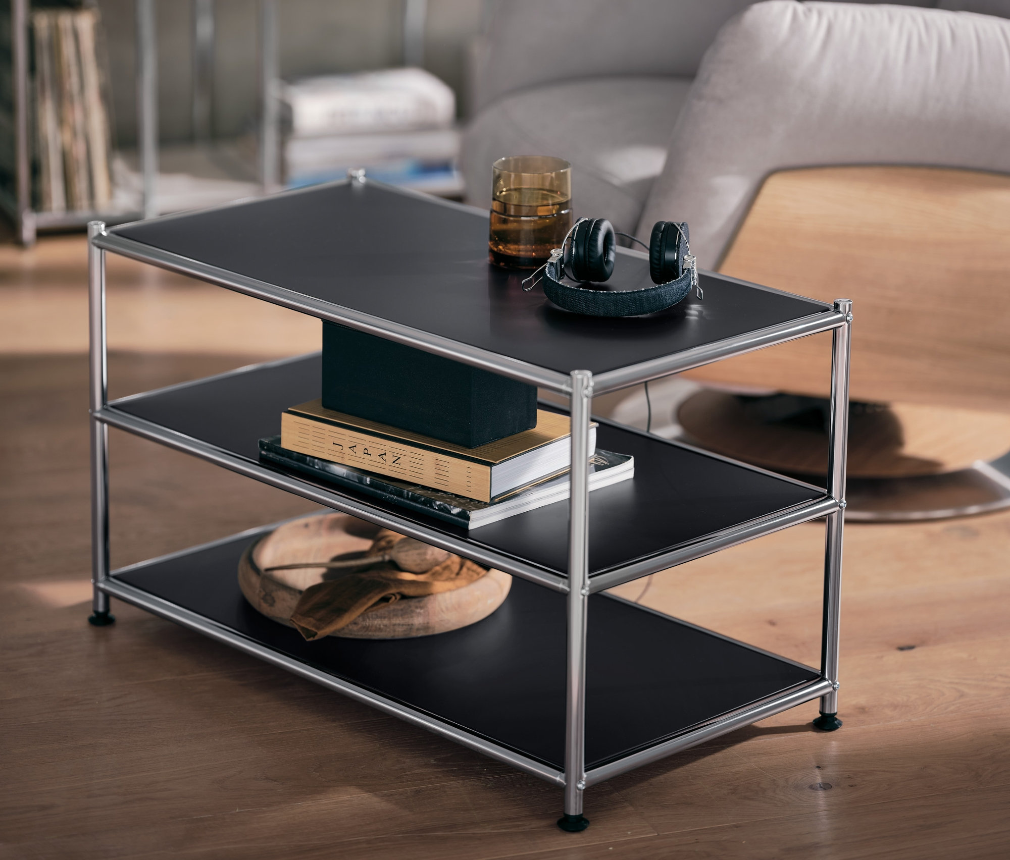 Table basse en métal noir « CN3 » avec verre et écouteurs sur l'étagère supérieure.