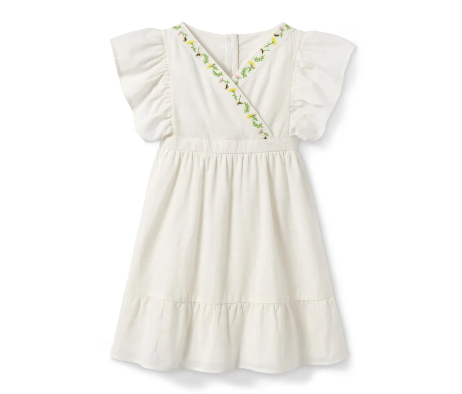 Une robe tissée blanche en coton bio avec des manches courtes et des broderies florales sur l'encolure.