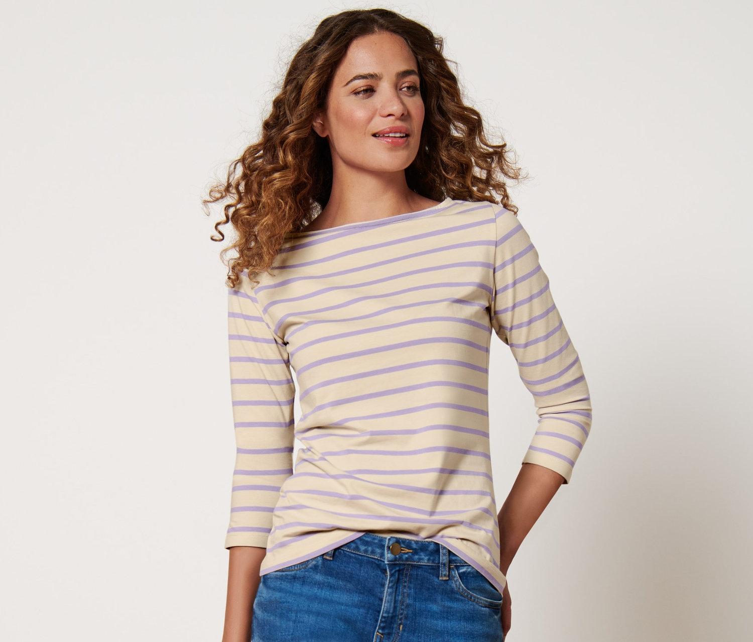 Une femme porte un t-shirt rayé beige et lilas à manches 3/4.