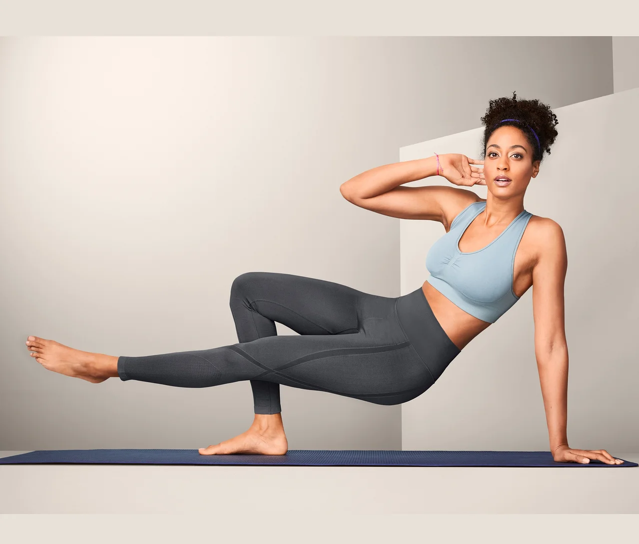 Femme faisant des exercices sur un tapis portant un legging modelant sans coutures.