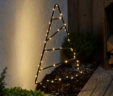 Un petit sapin d'extérieur à LED en métal est posé sur le sol à côté d'une allée en bois.