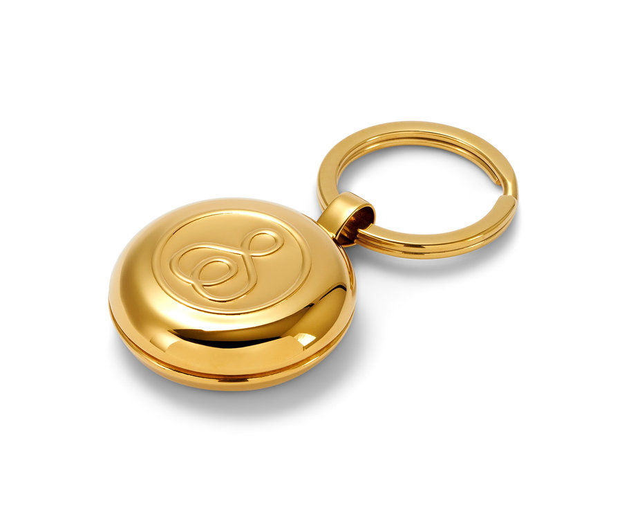 Porte-clés boîte à pilules doré sur fond blanc.