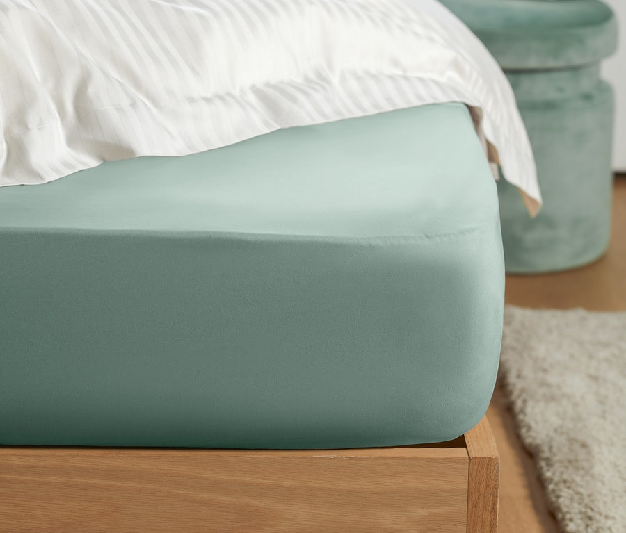 Gros plan d'un lit avec un drap-housse en jersey vert menthe.