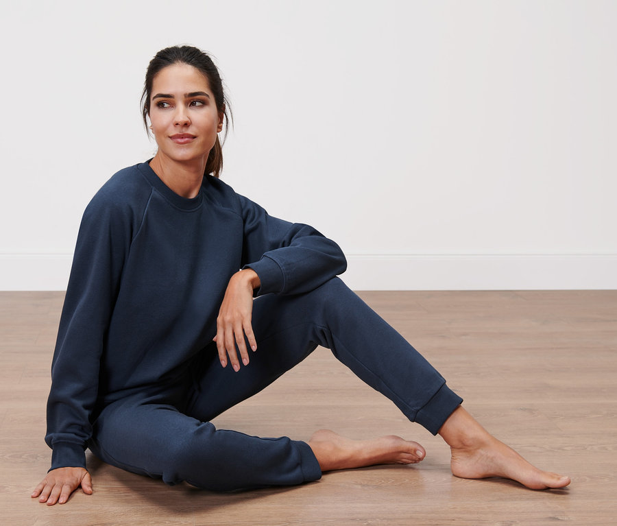 Femme assise par terre dans un survêtement d’intérieur bleu marine.