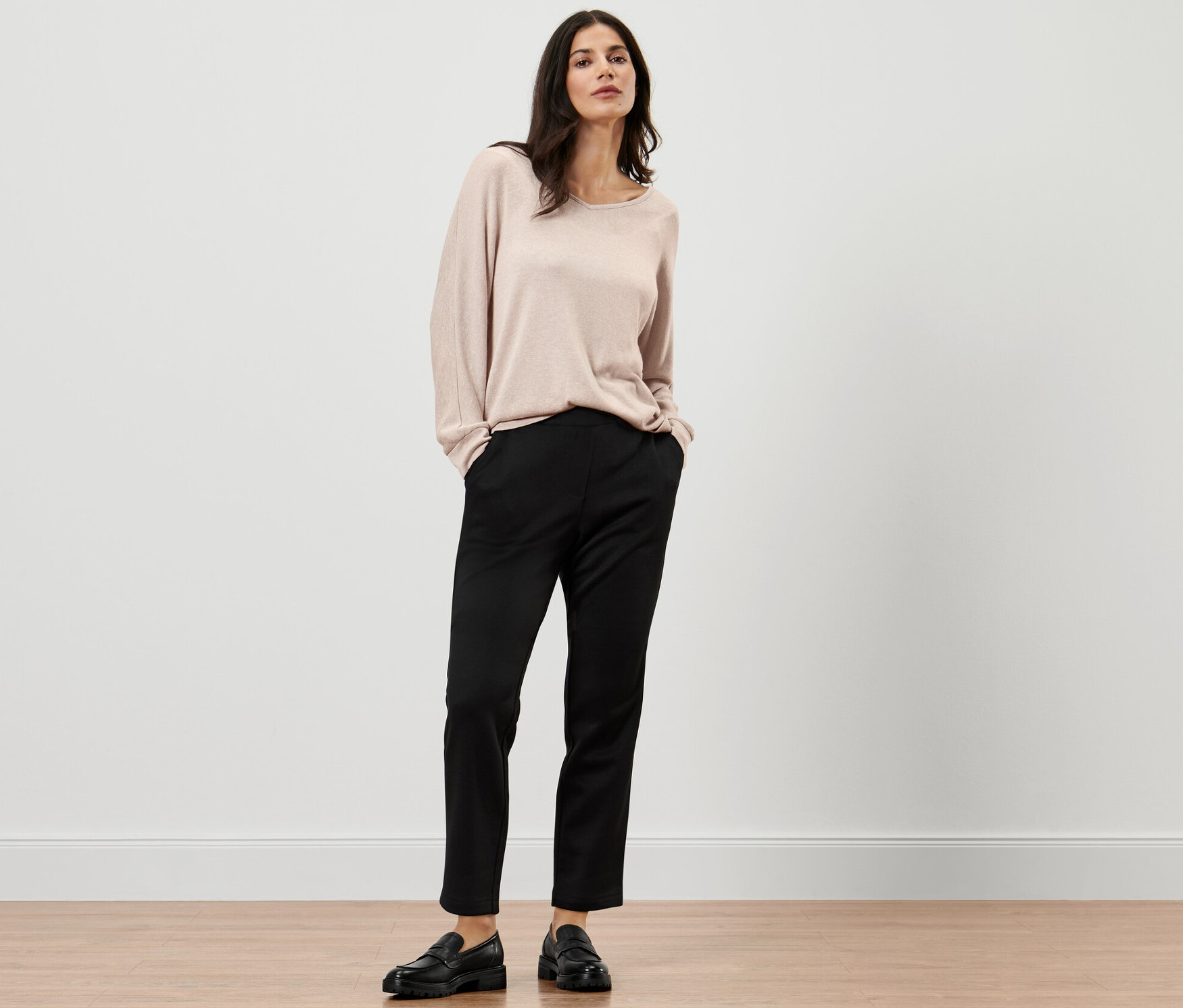 Femme posant en pantalon de jogging noir et pull.