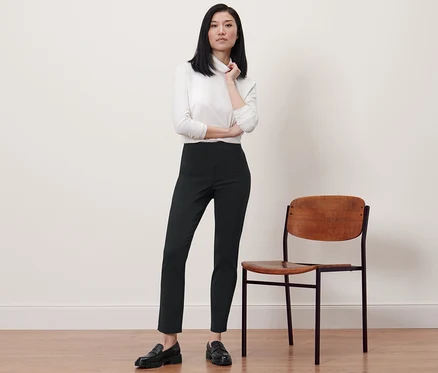 Femme posant en pantalon stretch noir à côté d'une chaise.