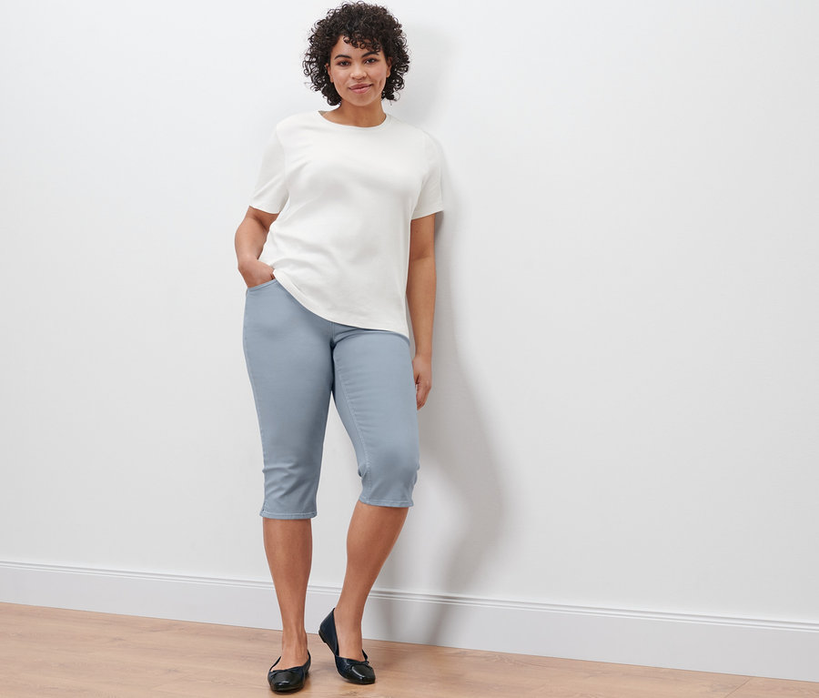 Une femme pose en denim Capri « Fit Mara » et un t-shirt basique crème.