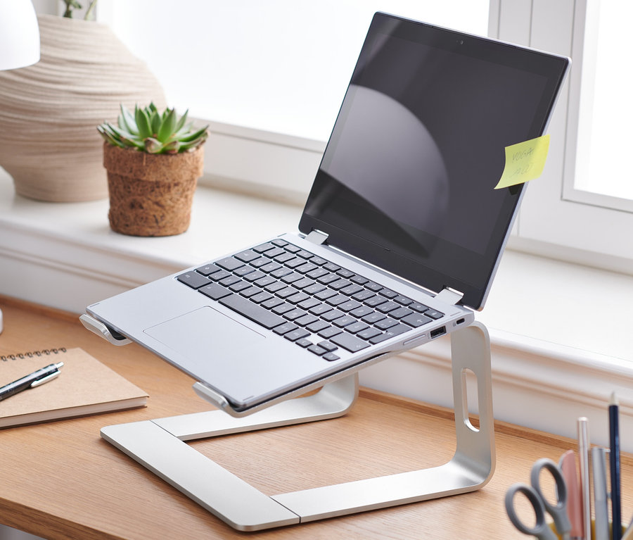 Ordinateur portable sur un support pour ordinateur portable sur une table en bois.