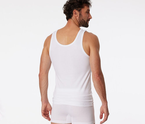 Homme vu de dos, légèrement tourné, portant un maillot de corps SCHIESSER blanc et un boxer blanc.