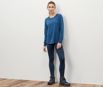Femme debout portant un legging de sport, un t-shirt à manches longues bleu rayé et des bottes.