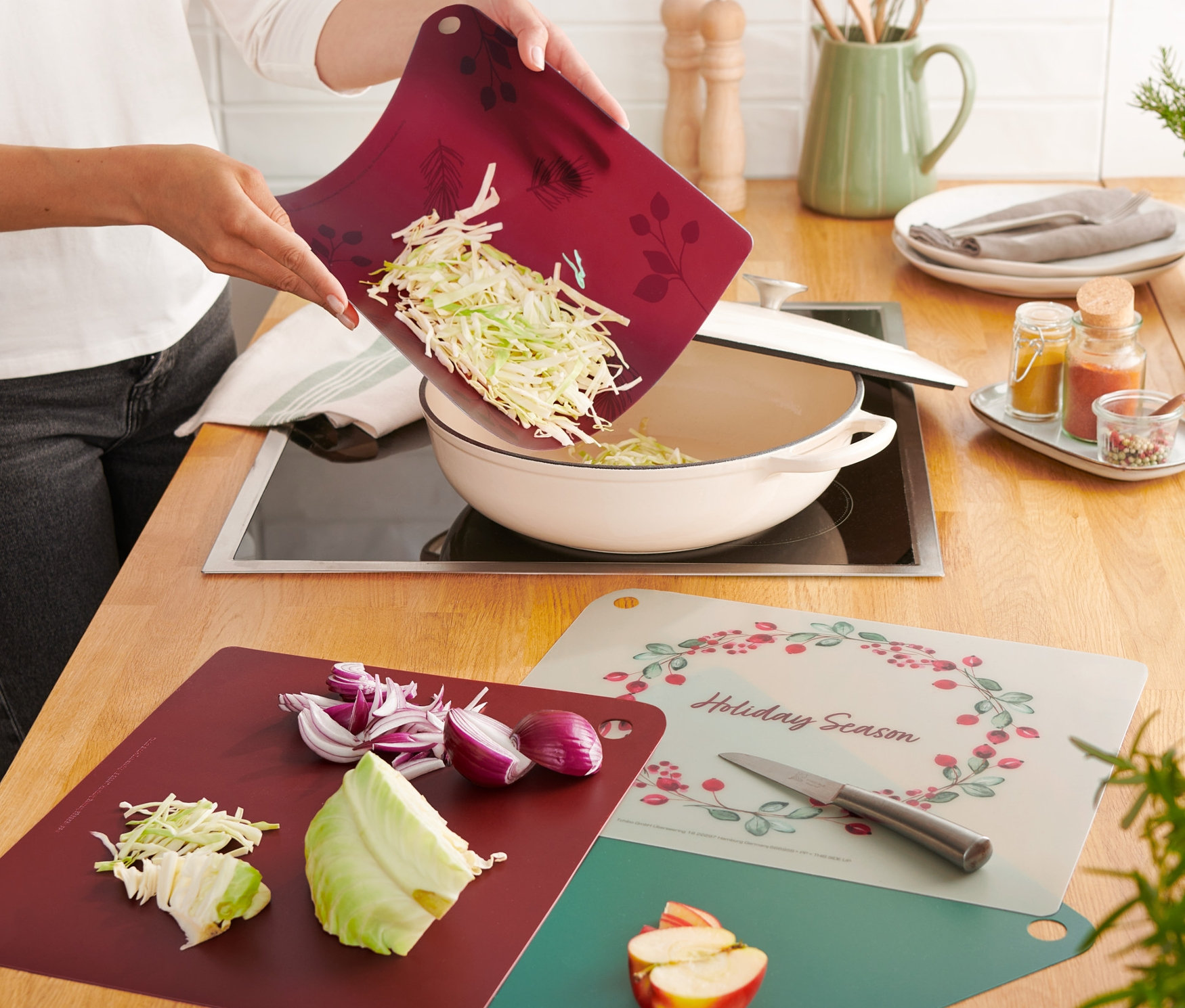 Une femme verse du chou coupé de l'une des 4 planches à découper dans une casserole.