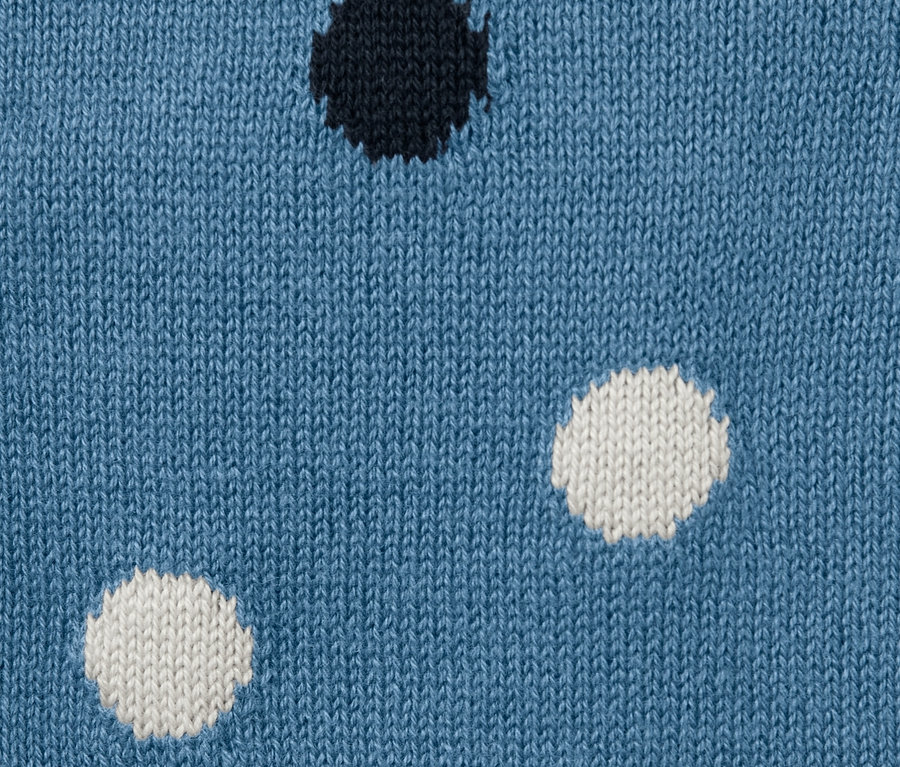 Gros plan sur un gilet en maille bleu pour tout-petit avec des pois noirs et blancs.