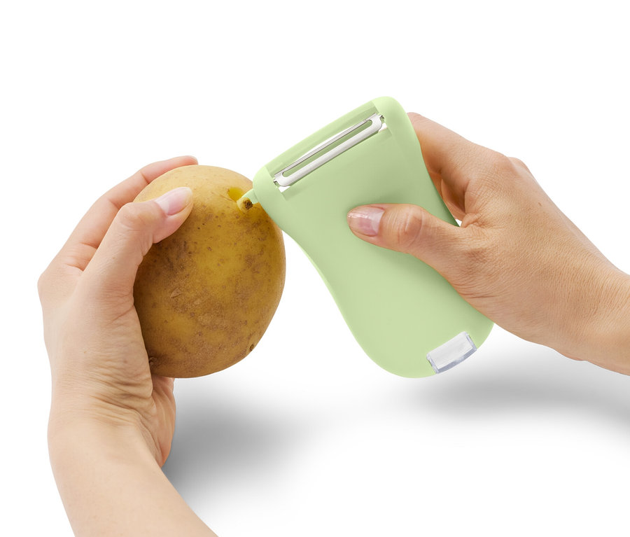 Une personne pèle une pomme de terre avec un éplucheur universel avec récipient collecteur.