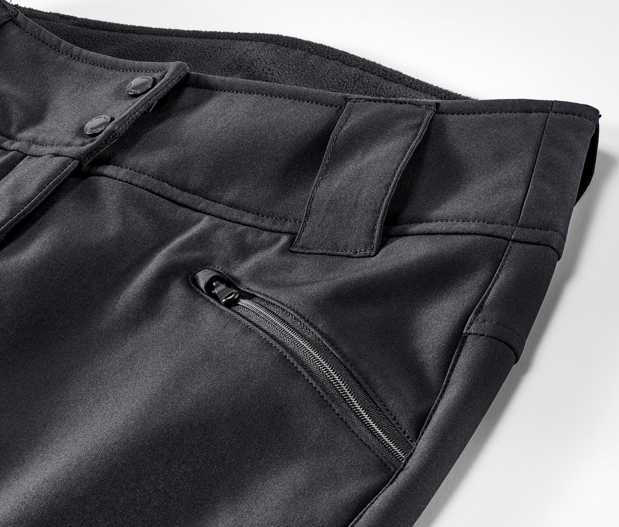 Gros plan sur un pantalon de ski noir avec fermeture à boutons et poche zippée.