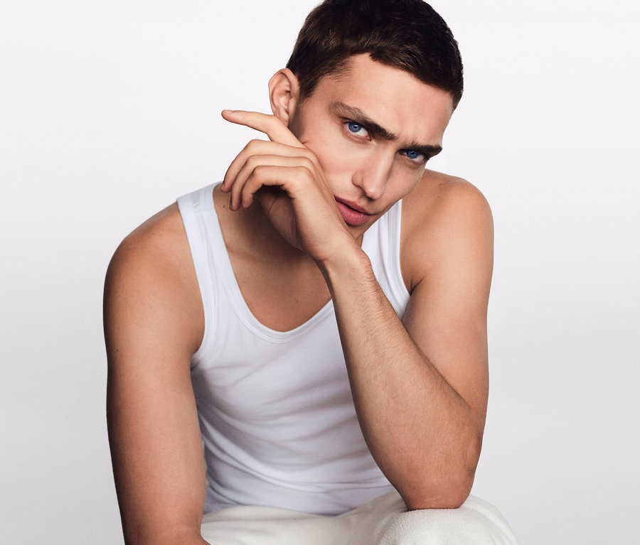 Un homme est assis, la main près du visage. Il porte 2 maillots de corps SCHIESSER en coton bio, blanc.