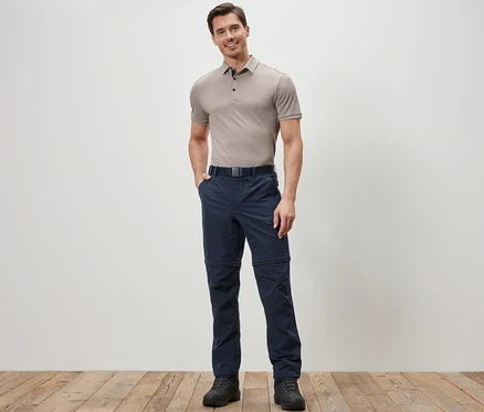 Un homme pose, portant un pantalon technique 2 en 1 bleu.