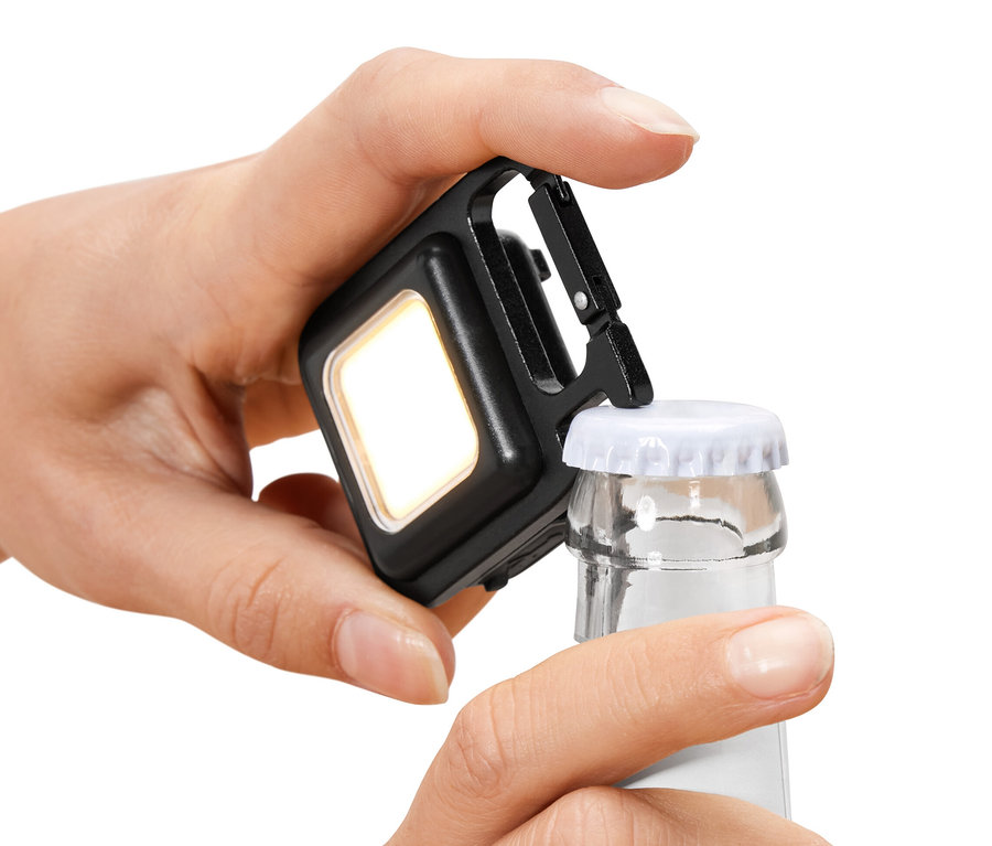 Une main ouvre une bouteille avec une lumière multifonction.