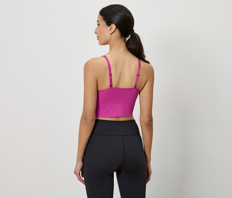 Une femme, vue de dos, porte un soutien-gorge de sport violet et un legging noir.