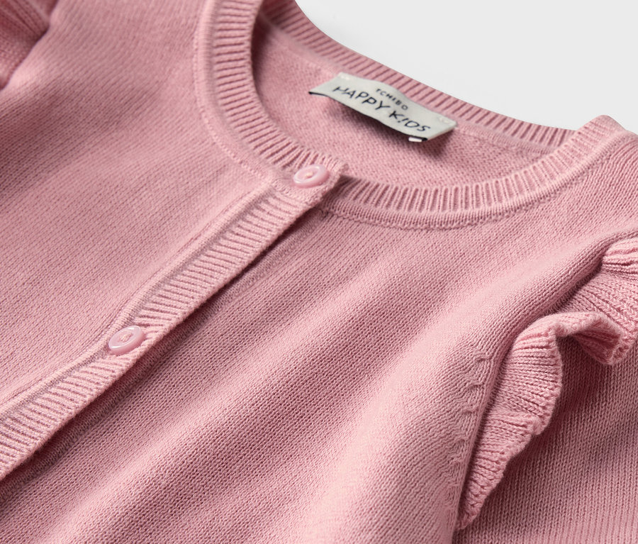 Gros plan sur une veste en maille rose pour enfant avec des volants.