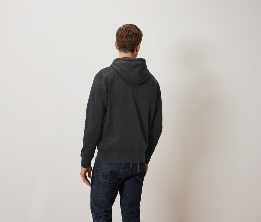 Un homme, vu de dos, porte un sweat à capuche gris foncé et un jean.