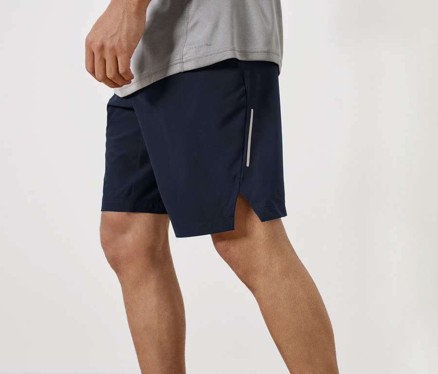 Un homme porte un short bleu marine et un t-shirt gris.