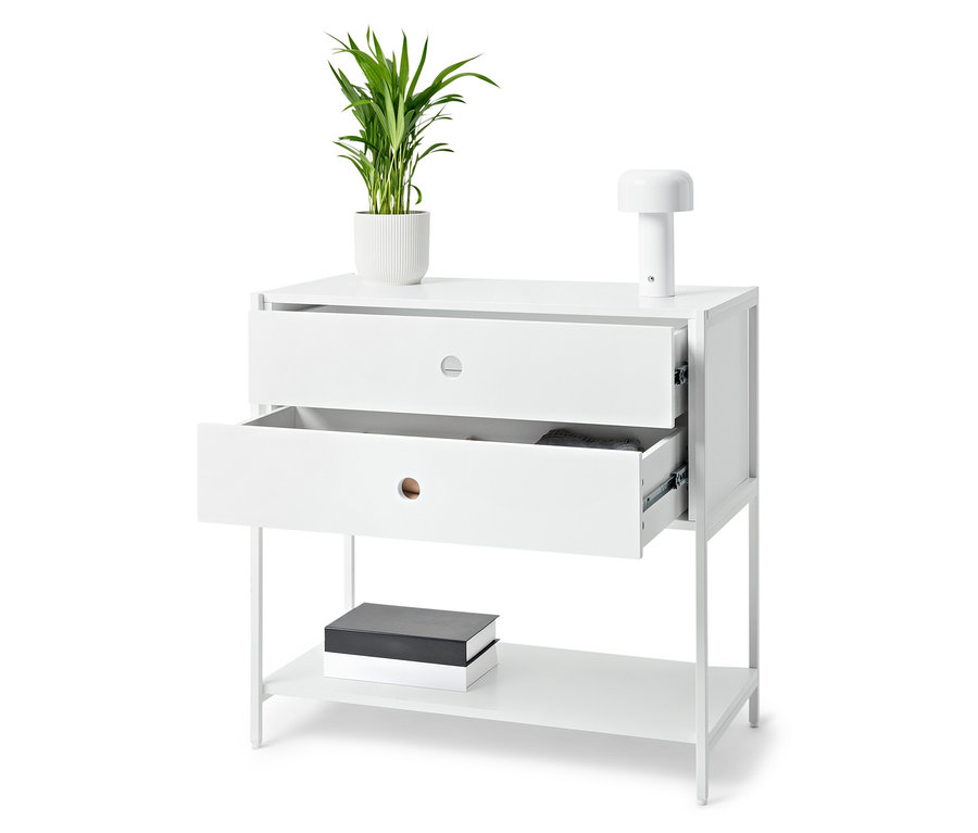 Table blanche avec deux tiroirs dont un est ouvert, sur laquelle se trouvent une plante en pot et une lampe. Des livres sont posés sur l'étagère inférieure.