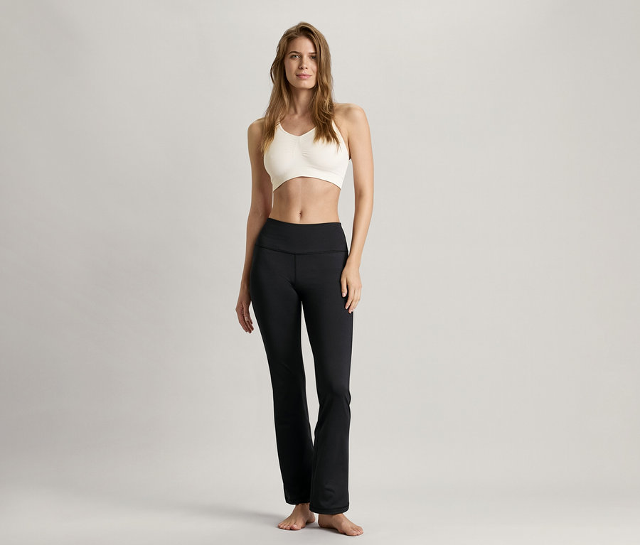 Femme debout portant un bustier de sport Seamless, blanc et un pantalon noir.