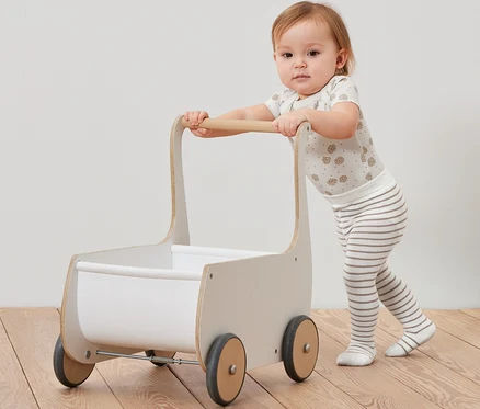 Un bébé pousse un chariot en bois et porte des collants de 5 paires de bas pour bébé.