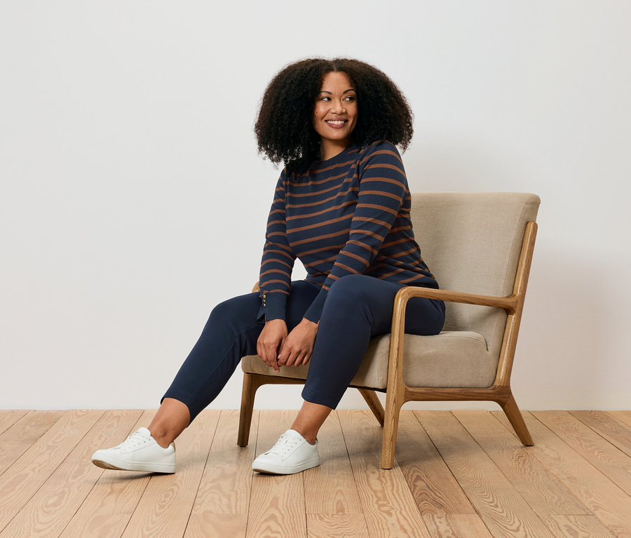 Femme assise dans un fauteuil portant un pantalon de jogging.
