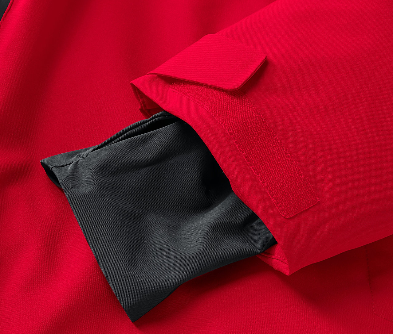 Détail d'une veste rouge avec une poche intérieure noire sur la manche.