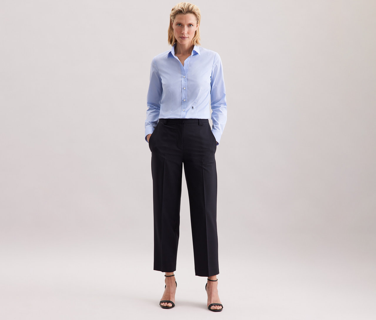 Femme portant un chemisier bleu clair Slim Fit non iron Seidensticker et un pantalon foncé.
