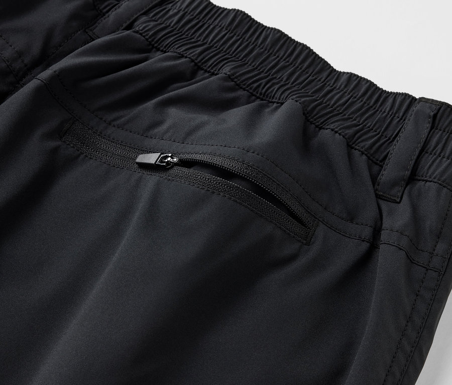 Détail d'un short technique en softshell noir avec une poche zippée.