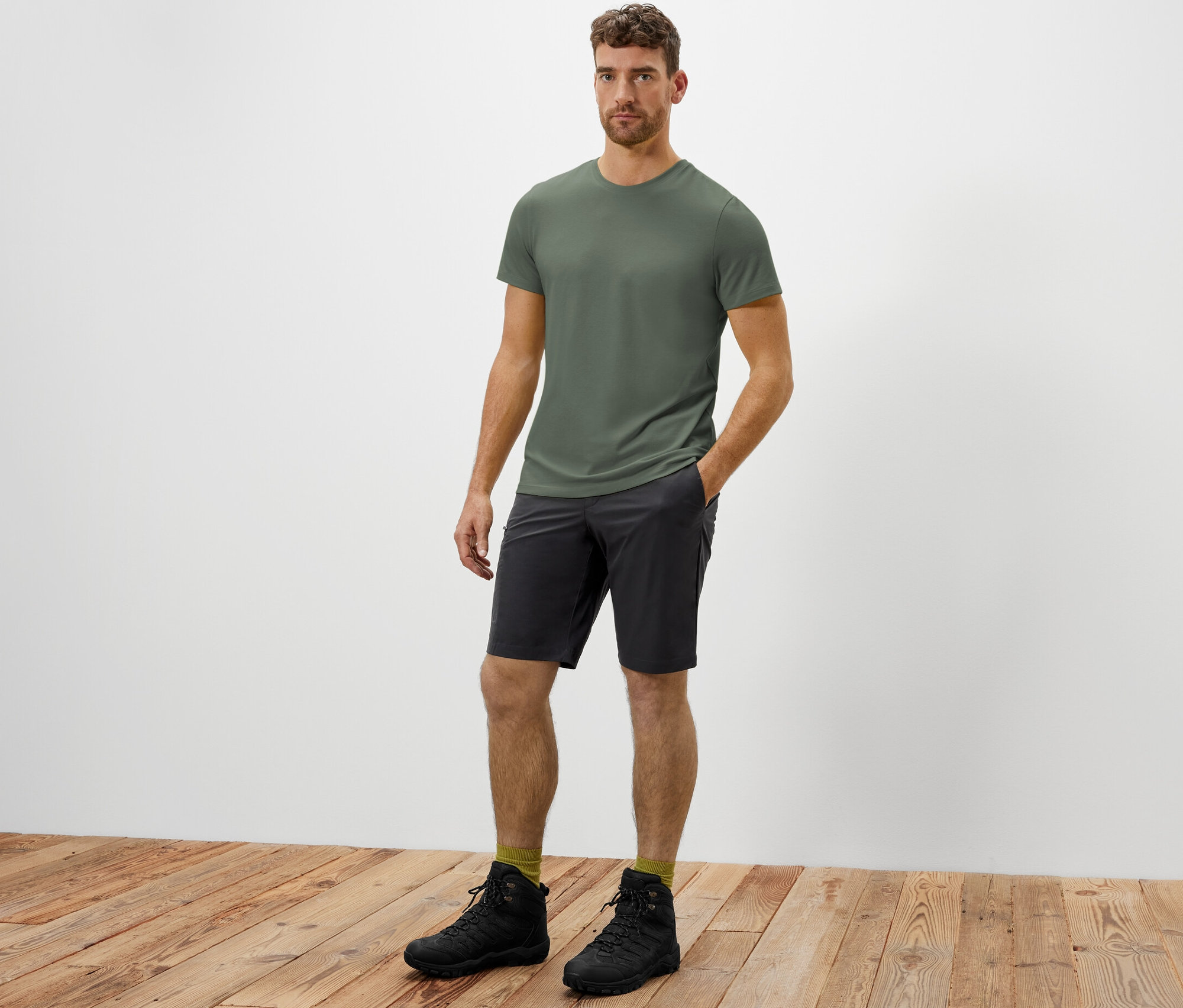 Un homme debout, la main dans la poche de son short fonctionnel en softshell.