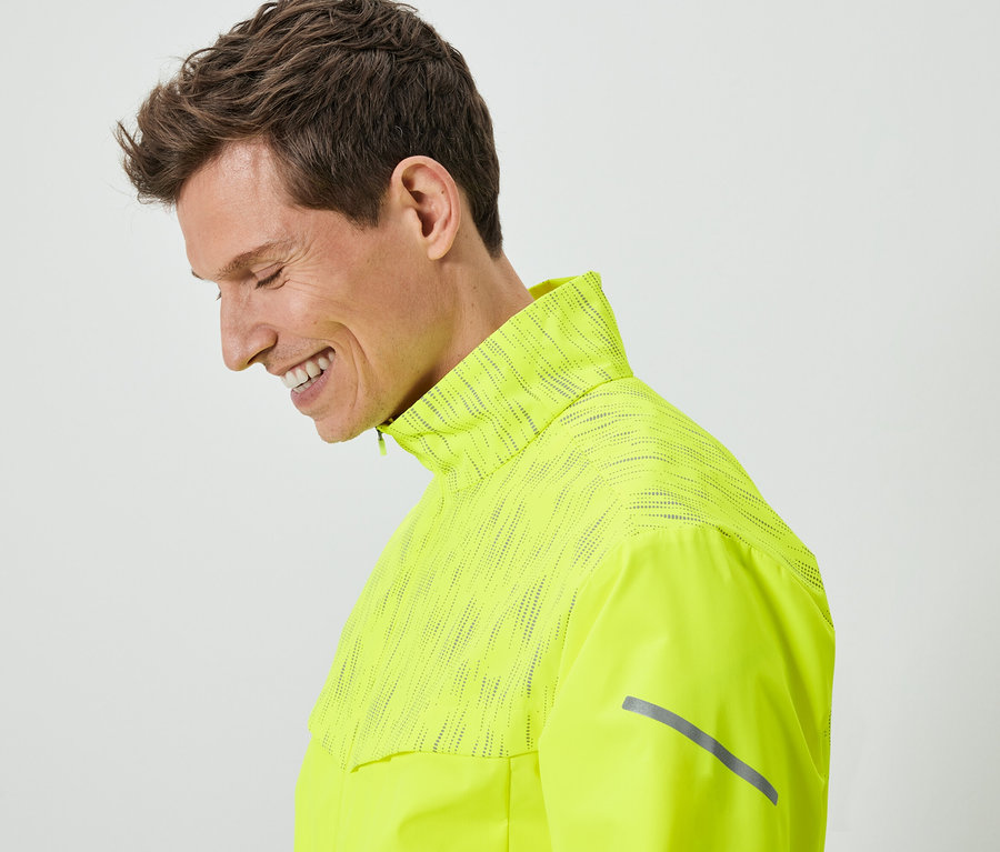 Homme souriant portant une veste texturée jaune néon.