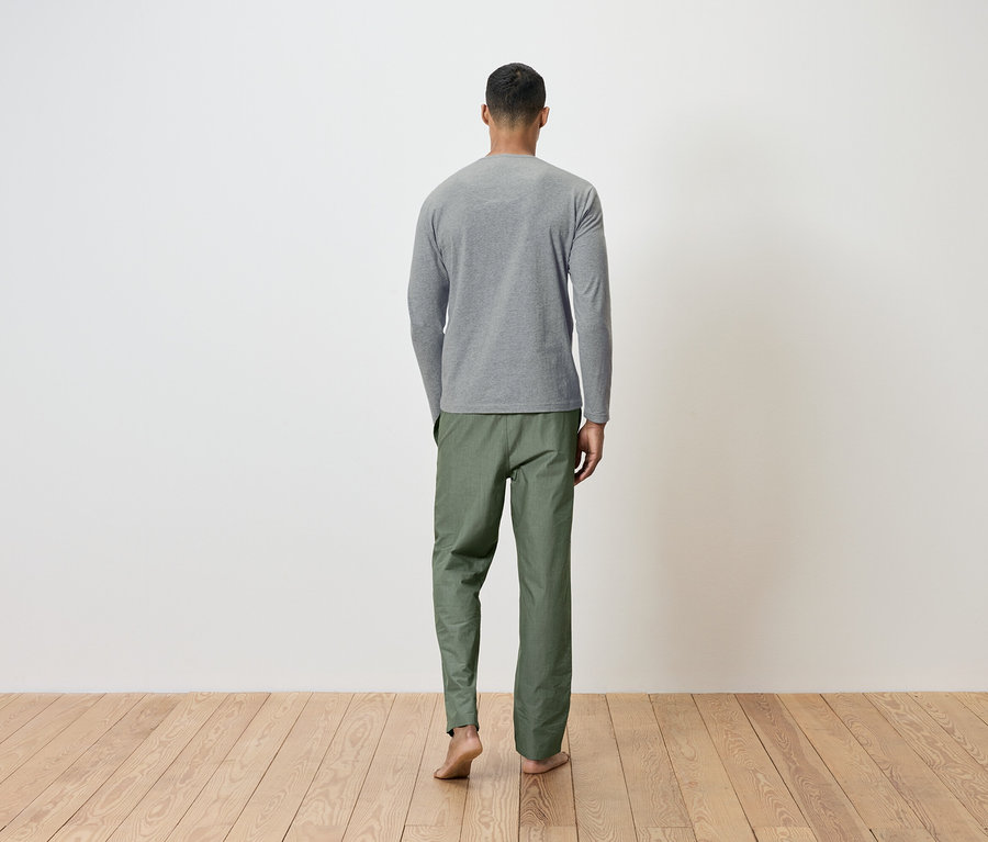 Un homme, vu de dos, porte un t-shirt gris à manches longues et un pantalon vert.