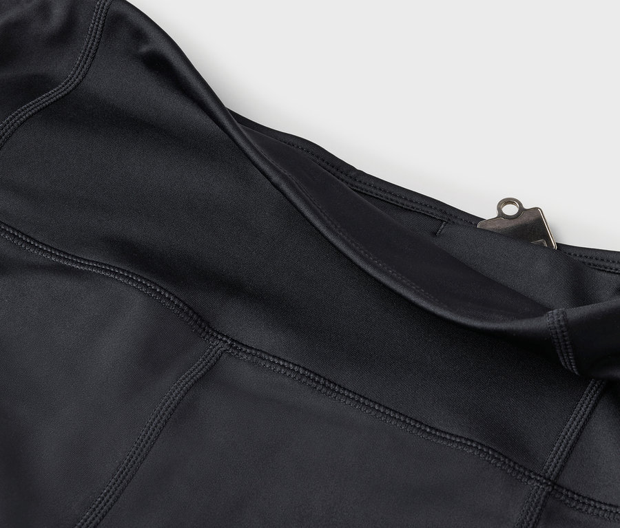 Détail de leggings noirs avec poche et clip argenté.