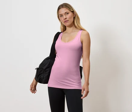 Femme portant un débardeur rose et un legging noir avec un sac noir sur l'épaule.
