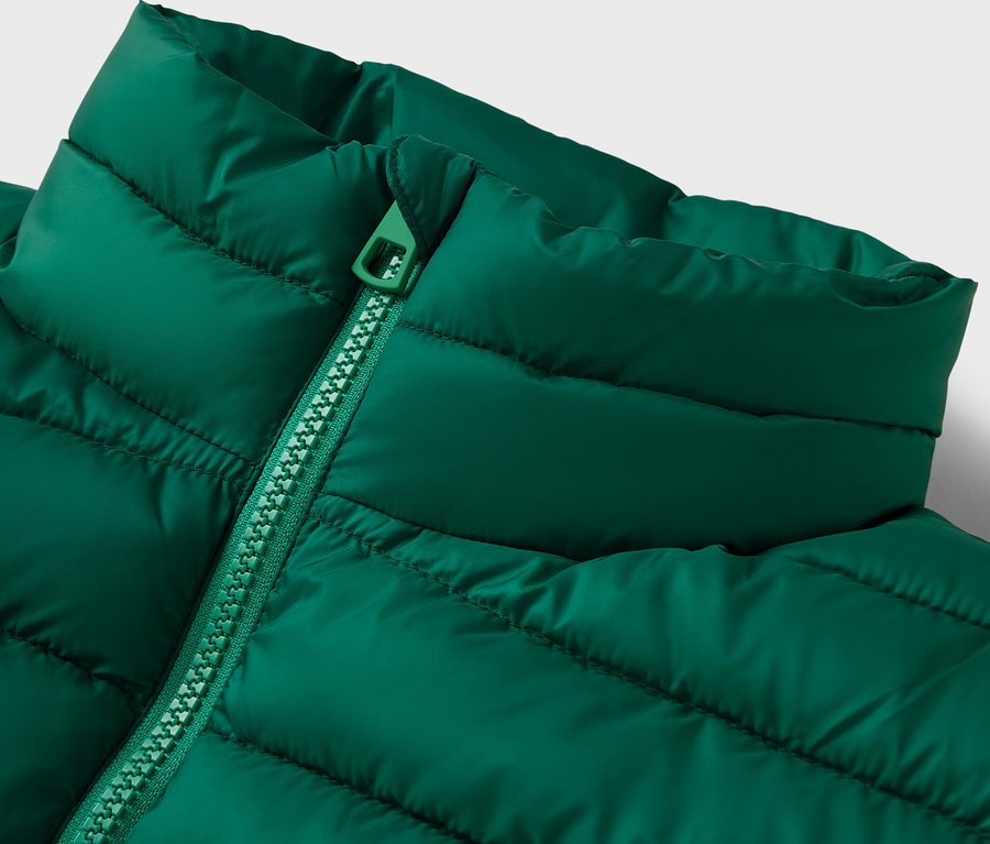 Gros plan d'une veste matelassée verte avec un col et une fermeture éclair.