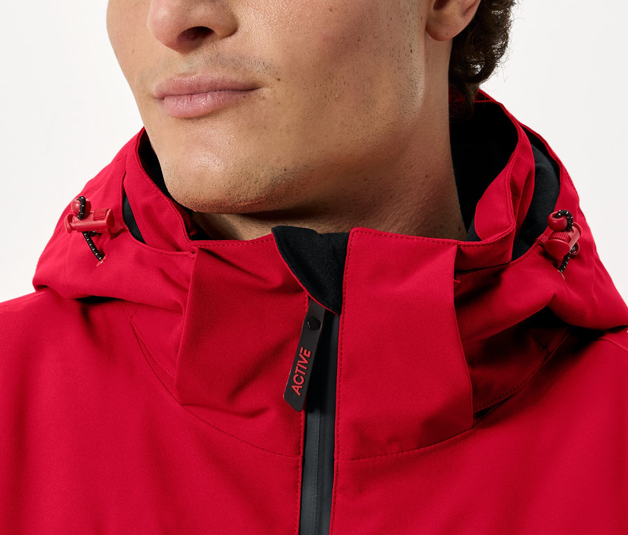 Un homme porte une veste rouge à capuche.