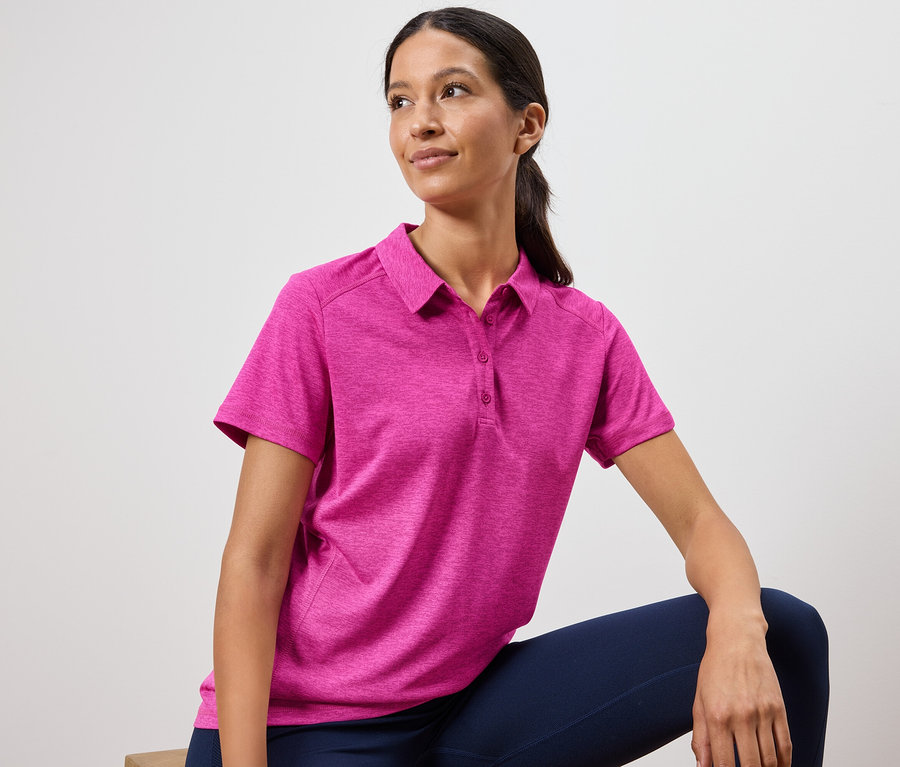 Une femme porte un polo rose et un legging bleu marine.