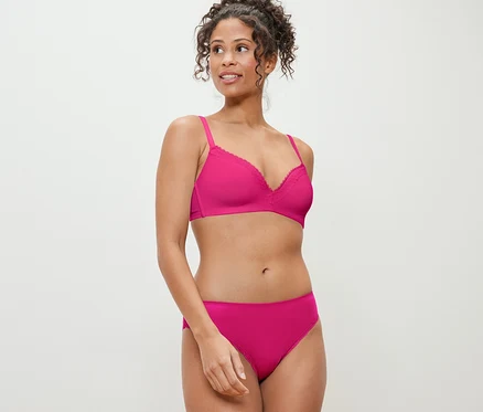 Une femme pose en soutien-gorge et 2 slips fuchsia.