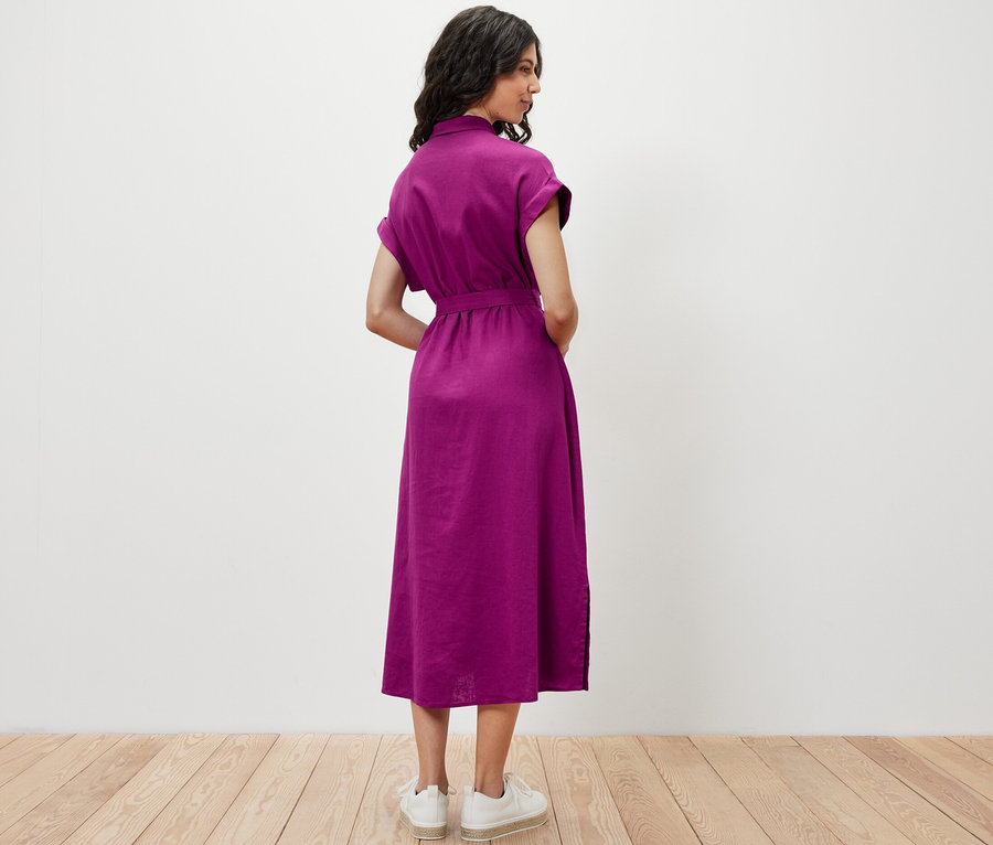 Une femme se tient dos à la caméra et porte une robe en lin.